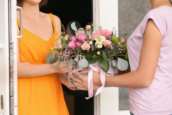 Young woman receiving gift box with beautiful flowers from courier�