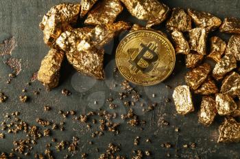 Gold nuggets and bitcoin on dark background�