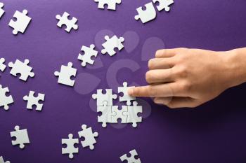 Hand of woman doing puzzle on color background�