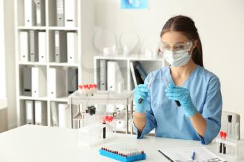 Female doctor working with blood samples at table in laboratory�