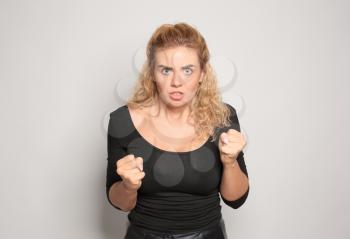 Portrait of angry young woman on light background�