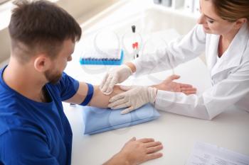 Female doctor preparing patient for blood draw in clinic�