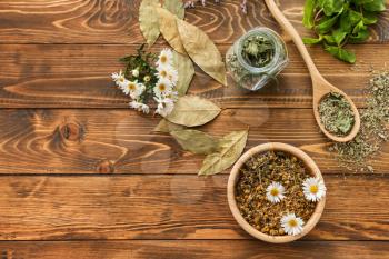 Bowl with dried chamomile flowers and herbs on wooden table�
