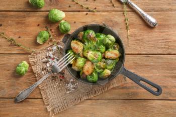 Pan with delicious roasted Brussels sprouts on wooden table, top view�
