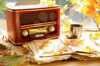 Old open book with retro radio and autumn leaves on windowsill�