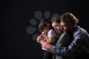 Praying family on dark background 