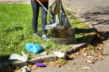 Woman gathering trash in park�
