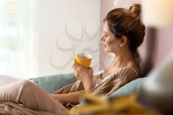 Woman drinking tea while resting at home on autumn day�