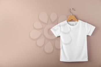 Hanger with blank white t-shirt on color background�