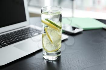 Glass of water with citrus fruits on dark table�