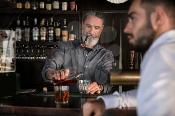 Senior barman serving client in pub 
