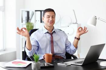 Businessman with a lot of work to do meditating in office�