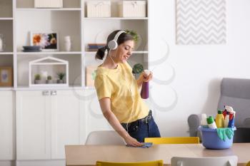 Young woman listening to music while cleaning her flat�