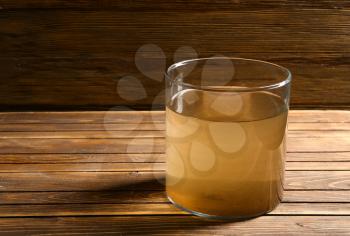 Glass of dirty water on wooden table�