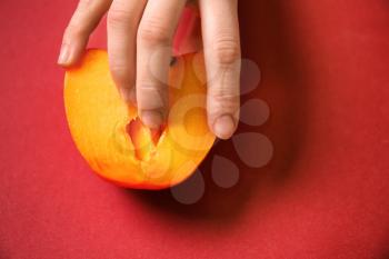 Woman touching half of juicy persimmon on color background. Erotic concept�