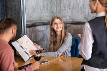 Waitress taking and order from young couple in restaurant�