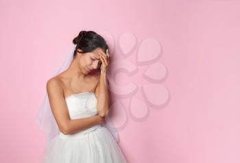 Stressed young bride on color background�