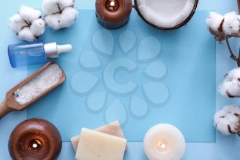 Spa composition with burning candles, cosmetics and cotton flowers on color background�