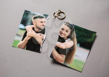 Torn photo of happy couple with rings on grey background. Concept of divorce�