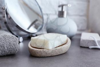 Dish with soap on grey table in bathroom�