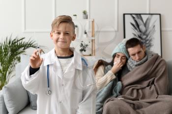 Cute little boy in doctor's uniform and his ill parents at home�