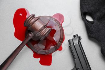 Gavel in stain of blood, gun and mask on white background. Concept of corrupt judge�