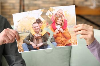 Unhappy couple with torn photo of theirs happy family. Concept of divorce�