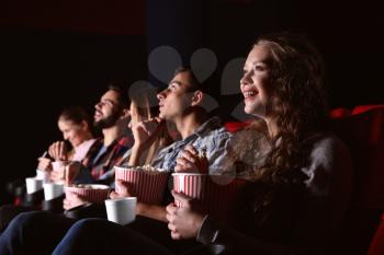 Friends eating popcorn while watching movie in cinema�