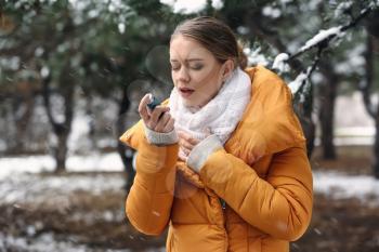 Young woman with inhaler having asthma attack outdoors�