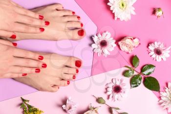 Young woman with beautiful pedicure and flowers on color background�