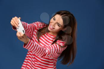 Emotional young woman playing mobile game on color background�