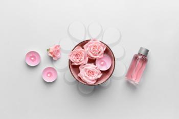 Spa composition with flowers, candles and essential oil on light background�