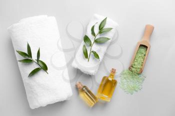 Spa composition with towels, sea salt and essential oil on light background�