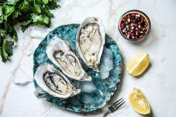 Plate with tasty cold oysters on light table�