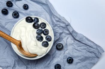 Bowl with tasty yogurt and blueberry on light background�
