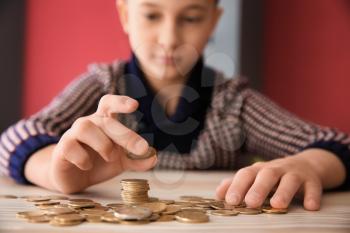 Cute little boy with coins sitting at table. Concept of child support�