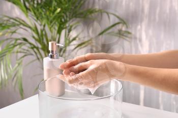 Woman washing hands with soap in bathroom�