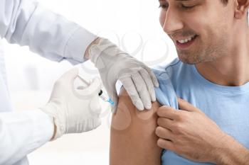 Doctor vaccinating male patient in clinic�