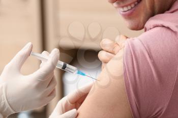 Doctor vaccinating man against flu in clinic�