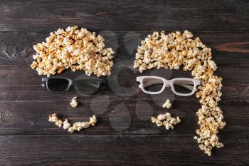 Funny couple made of popcorn on dark wooden background�