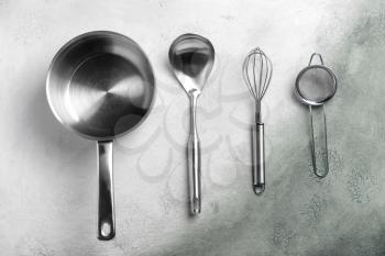Stainless steel kitchen utensils on grey background�