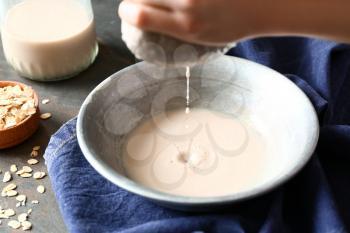 Woman preparing tasty oat milk on table, closeup�