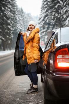 Young woman near car at winter resort�