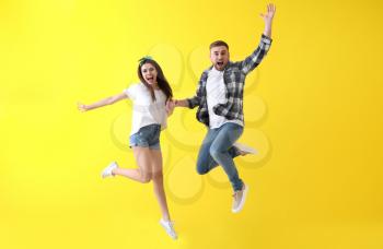 Jumping young couple on color background�