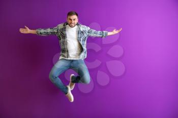 Jumping young man on color background�