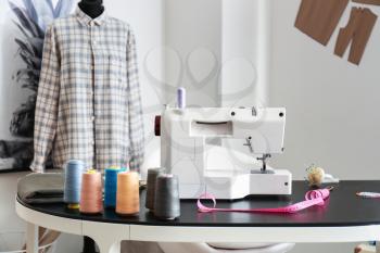 Sewing machine with accessories on tailor's workplace in atelier�