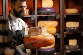 Male seller with delicious cheese in store�
