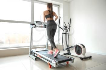 Sporty young woman on treadmill in gym�