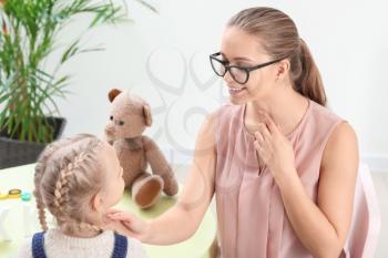 Speech therapist working with little girl in office�