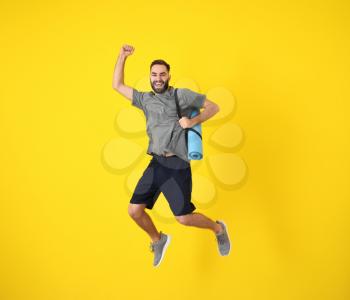 Young sporty man jumping against color background�